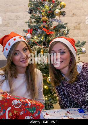 Amici sorridente sotto albero di Natale con confezioni regalo presente Foto Stock