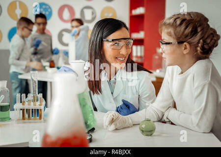 Piacevole parlare. Silhouette di ragazzi che in piedi sul background e facendo esperimento chimico insieme Foto Stock