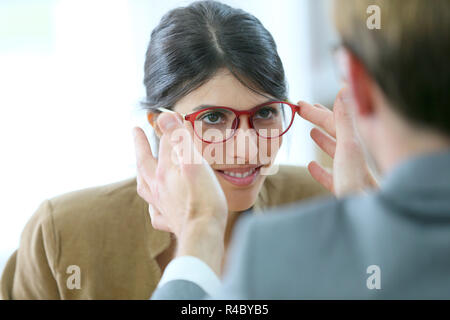 Ottico della sperimentazione di nuovi occhiali sulla donna Foto Stock