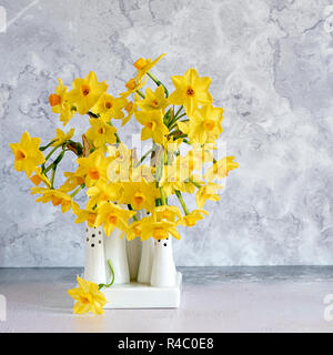 Close-up, still-life immagine dei bellissimi fiori di primavera di Narciso 'tete-a-tete' una nana Daffodil. Fiori recisi in porcellana bianca vasi Foto Stock