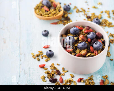 Fatta in casa tè verde Matcha granola nella ciotola sul pastello sfondo turchese. Avena granola con bacche di goji, frutta secca, semi e noci. Un sano breakfast o Foto Stock