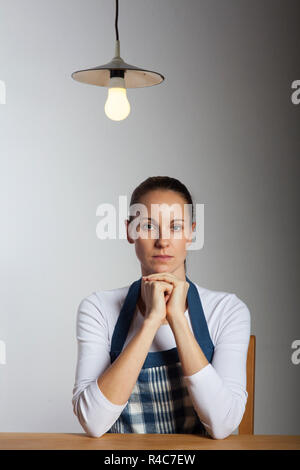 La donna in un grembiule in una tabella Foto Stock