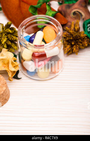 Varie pillole e capsule in un contenitore di vetro con il verde Foto Stock