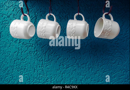 Tazze da caffè appeso su ganci di blu parete cucina arredamento moderno Foto Stock
