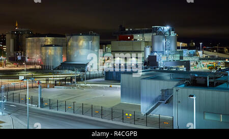 Moderno terminale di grano di notte. Serbatoi in metallo di ascensore. Granella di essiccazione di costruzione complessa. Grani commerciale di sementi o silos a Seaport. Storage di acciaio per il raccolto agricolo Foto Stock