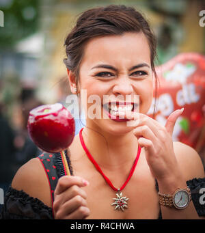 Donna attraente tenendo un rosso mela caramellate al Oktoberfest Foto Stock