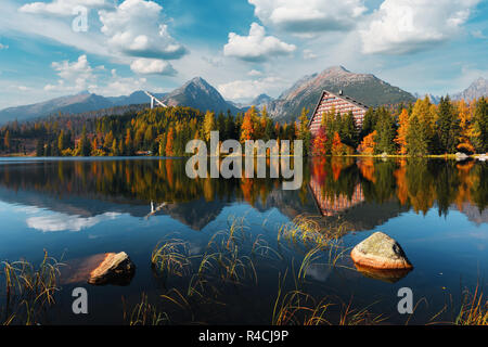Pittoresca vista autunnale del lago il villaggio di Strbske Pleso negli Alti Tatra National Park, Slovacchia. L'acqua chiara con riflessi arancione di larice e di alta montagna Foto Stock