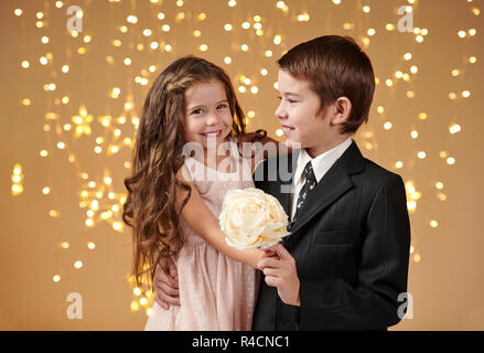 Due bambini di un ragazzo e una ragazza sono in luci di Natale, sfondo giallo, vacanze inverno concept Foto Stock