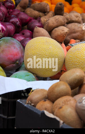 Close-up di un supporto in un negozio di vendita di frutta e verdura come meloni, viola le cipolle, kiwi, patate dolci, papaia, ecc. Foto Stock