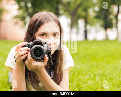 Ragazza con fotocamera sdraiarsi sull'erba Foto Stock