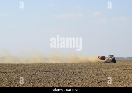 Il trattore corre sul campo e rende il fertilizzante nel terreno. Fertilizzanti dopo aratura del campo. Foto Stock