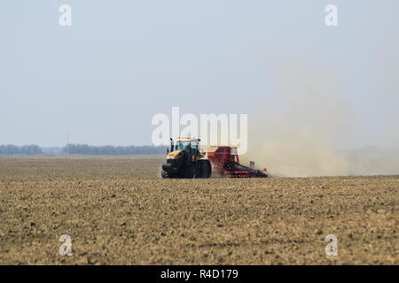 Il trattore corre sul campo e rende il fertilizzante nel terreno. Fertilizzanti dopo aratura del campo. Foto Stock