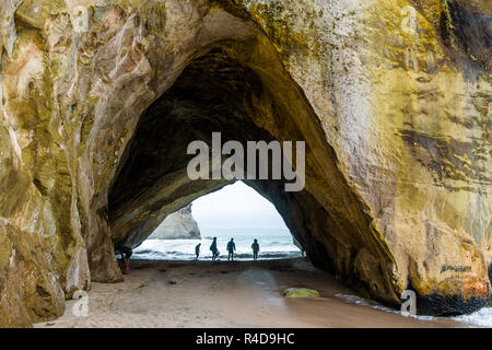 Arco di roccia in Te Whanganui-A-Hei (Cove della cattedrale) riserva marina, Nuova Zelanda. Silhouette di persone vicino al litorale. Foto Stock