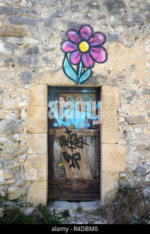 Surreale porta Graffiti & fiore stilizzato dipinta su una casa in rovina nel villaggio abbandonato di Le Vieux-Noyers Noyers Provence Francia Foto Stock