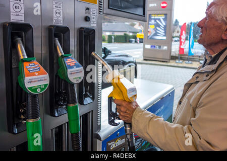 Uomo anziano scelta del carburante diesel ugello della pompa e la visione di caro prezzo al distributore di carburante di gas stazione per il rifornimento di carburante la sua auto in Belgio, Europa Foto Stock