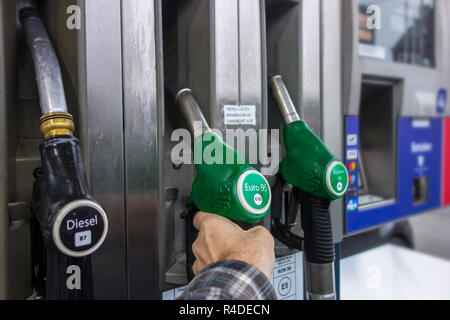 L'uomo la selezione di pompa di alimentazione di benzina ugello in corrispondenza della stazione di gas per il rifornimento di carburante la sua auto in Europa Foto Stock