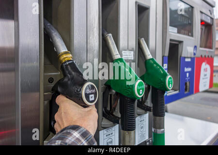 L'uomo la selezione di pompa del gasolio ugello in corrispondenza della stazione di gas per il rifornimento di carburante la sua auto in Europa Foto Stock