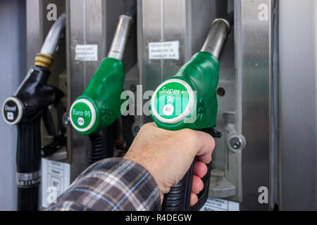 L'uomo la selezione di pompa di alimentazione di benzina ugello in corrispondenza della stazione di gas per il rifornimento di carburante la sua auto in Europa Foto Stock