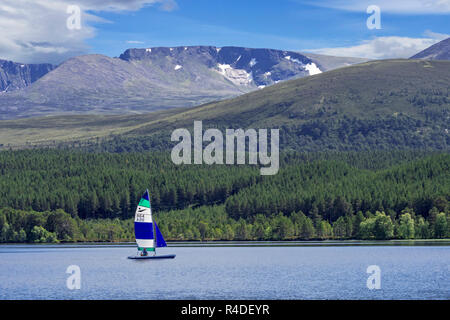 Barca a vela sul Loch Morlich davanti al Cairngorm monti Cairngorms National Park, Badenoch e Strathspey, Highland, Scotland, Regno Unito Foto Stock