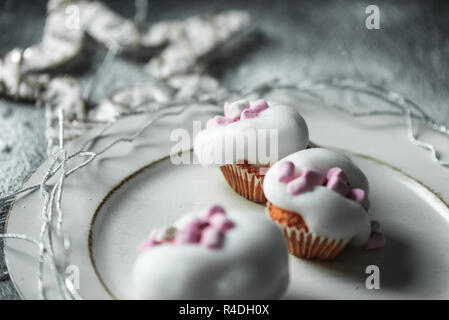 Sweet winter tortine con bianco, luce di schiuma di zucchero e rosa marshmallows sullo sfondo di una decorazione di Natale con la neve Foto Stock