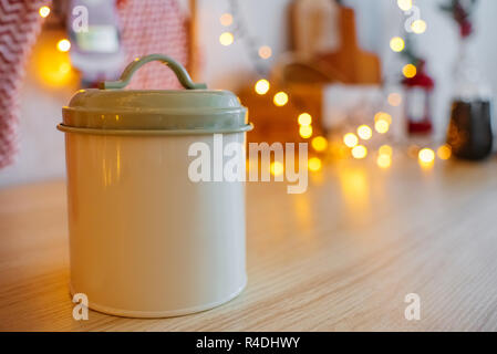 Barattolo di latta per prodotti sfusi. Pulire lo sfondo per il testo del titolo. Decorazioni di Natale ghirlanda bokeh. Cucina nuovo anno 2019 Foto Stock