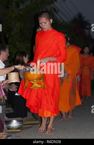 A partire prima di alba arancio-derubato il Laos i monaci buddisti prendere alms dall'dedicato ogni giorno di prima mattina - Luang Prabang, nel nord del Laos. Foto Stock