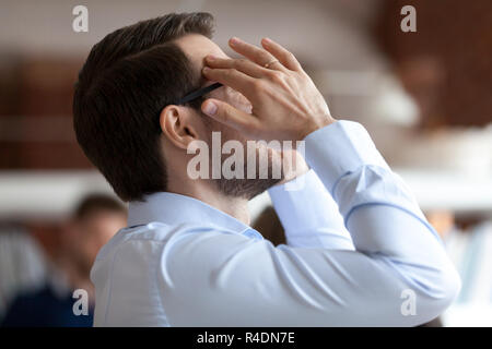 Sottolineato imprenditore è templi di massaggio, sensazione di mal di testa Foto Stock