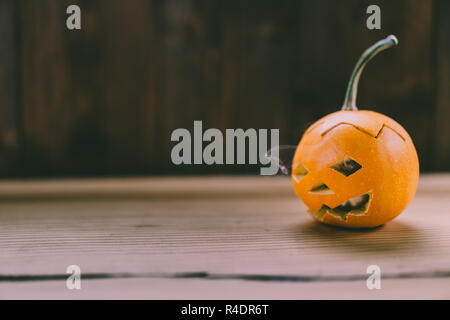 Primo piano del Bambino scolpita la zucca sulla botte sfondo con i fumi in uscita dei suoi occhi e bocca - oggetto isolato con sfondo sfocato, H Foto Stock