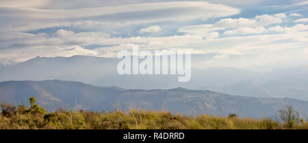Strati di montagne della Sierra Nevada , quelle più alte incappucciate di neve in una giornata di sole con soffici nuvole. Andalusia, Spagna Foto Stock