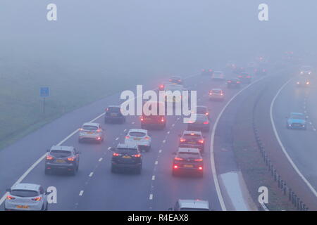 Leeds, West Yorkshire, Regno Unito. Il 27 novembre 2018. Gli automobilisti battaglia attraverso una fitta nebbia sul loro tragitto durante le ore di punta sull'autostrada M1 a Leeds. Foto Stock