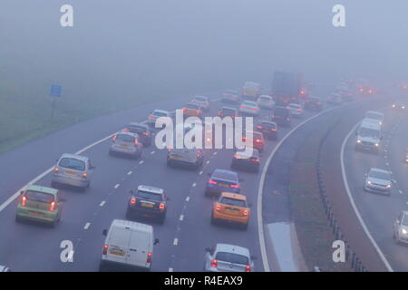 Leeds, West Yorkshire, Regno Unito. Il 27 novembre 2018. Gli automobilisti battaglia attraverso una fitta nebbia sul loro tragitto durante le ore di punta sull'autostrada M1 a Leeds. Foto Stock