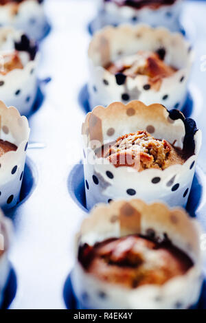 In prossimità di alcuni appena sfornato di zucca muffin rivestiti su un alluminio vassoio da forno per la Festa di halloween visualizzata su un blu scheda rustico, laici piatta vista dall'alto,nat Foto Stock