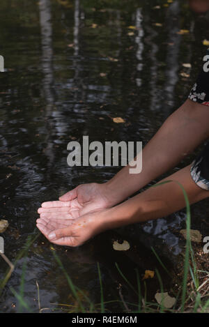 Donna immergendo la mano in un fiume, Bulgaria Foto Stock