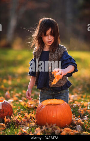 Ragazza intagliare una zucca di Halloween nel giardino, Stati Uniti Foto Stock