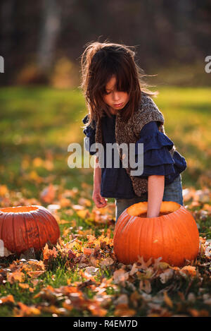 Ragazza intagliare una zucca di Halloween nel giardino, Stati Uniti Foto Stock