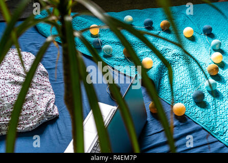Grigio Laptot posa sul materasso con coperchio color turchese, alcuni cuscini e uno sfondo bianco - con decorazione di Natale luci sul letto Foto Stock