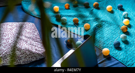 Grigio Laptot posa sul materasso con coperchio color turchese, alcuni cuscini e uno sfondo bianco - con decorazione di Natale luci sul letto Foto Stock