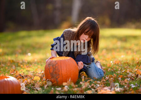 Ragazza intagliare una zucca di Halloween nel giardino, Stati Uniti Foto Stock