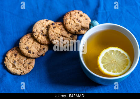 Tè con limone e biscotti al cioccolato con la posa sul materasso - sfocata coperchio color turchese in background con cuscino Foto Stock