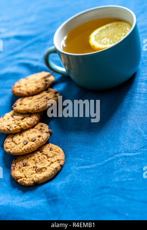 Tè con limone e biscotti al cioccolato con la posa sul materasso - sfocata coperchio color turchese in background con cuscino Foto Stock