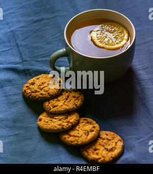 Tè con limone e biscotti al cioccolato con la posa sul materasso - sfocata coperchio color turchese in background con cuscino Foto Stock