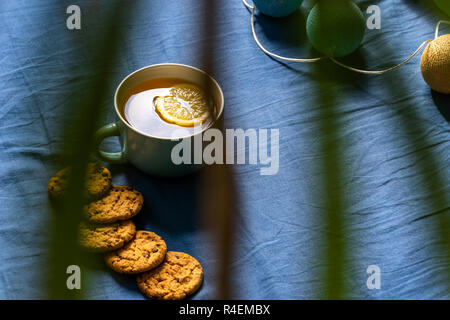 Tè con limone e biscotti al cioccolato con la posa sul materasso - sfocata coperchio color turchese in background con cuscino Foto Stock