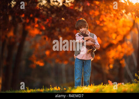 Ragazzo accanto all'aperto cuddling un pollo, Stati Uniti Foto Stock