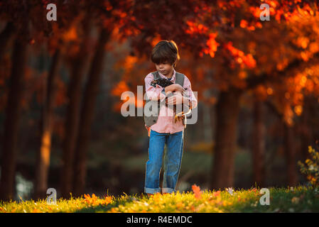 Ragazzo accanto all'aperto cuddling un pollo, Stati Uniti Foto Stock