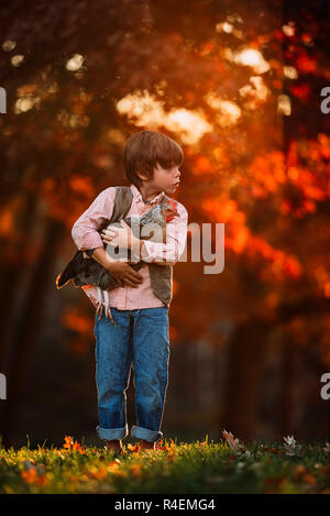 Ragazzo accanto all'aperto cuddling un pollo, Stati Uniti Foto Stock