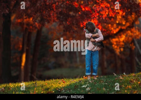 Ragazzo accanto all'aperto cuddling un pollo, Stati Uniti Foto Stock