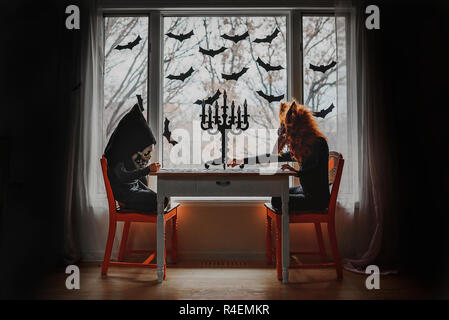 Due bambini in costumi di Halloween seduto da una finestra facendo un puzzle, Stati Uniti Foto Stock