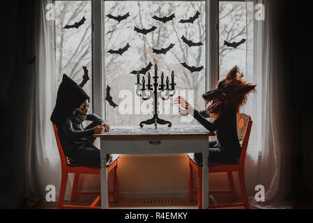 Due bambini in costumi di Halloween seduto da una finestra facendo un puzzle, Stati Uniti Foto Stock