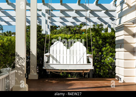 Patio in legno bianco appeso nuovo swing in molla esterna verde del giardino nel portico del cortile sul retro di casa zen, mobili sospesi, nessuno in Florida tropica Foto Stock