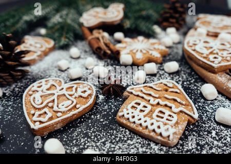 Close up Natale gingerbread cookies nel cuore e nella forma della casa sul tavolo con marshmellows e altre decorazioni. Foto Stock